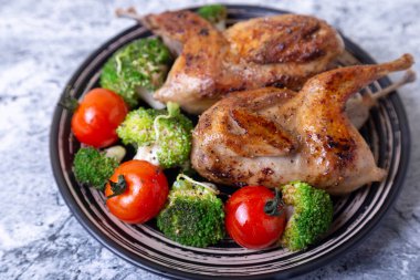 Brokoli ve kiraz domatesli bıldırcın kızartması. Siyah plaka, mermer arka plan. Seçici odak, kapat.