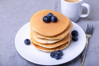 Yabanmersinli krep. Arka planda bir fincan kahve. Geleneksel Amerikan gözlemeleri. Yakın plan..