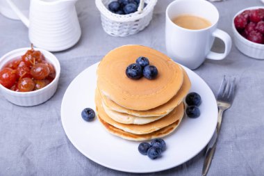 Yabanmersinli krep, kiraz ve küçük elma reçeli. Arka planda bir fincan kahve ve sos kabı. Geleneksel Amerikan gözlemeleri. Yakın plan..