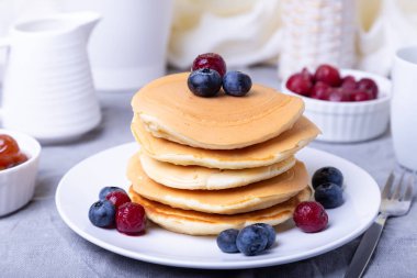 Yabanmersinli krep, kiraz ve küçük elma reçeli. Arka planda bir fincan kahve ve sos kabı. Geleneksel Amerikan gözlemeleri. Yakın plan..