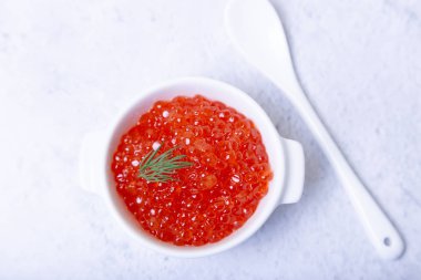 Beyaz bir fincanda kırmızı havyar (somon havyarı). Beyaz arkaplan, seçici odak, yakın plan.