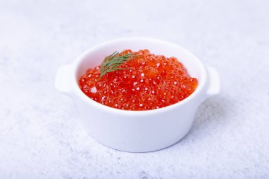 Beyaz bir fincanda kırmızı havyar (somon havyarı). Beyaz arkaplan, seçici odak, yakın plan.