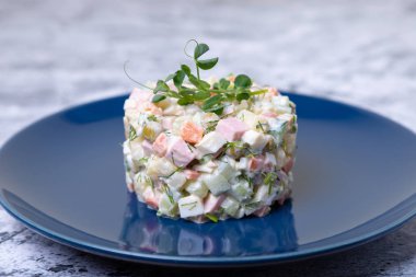 Mavi tabakta bezelye filizleriyle süslenmiş Olivier salatası. Geleneksel Yeni Yıl ve Noel Rus salatası. Yakın çekim, seçici odaklanma.