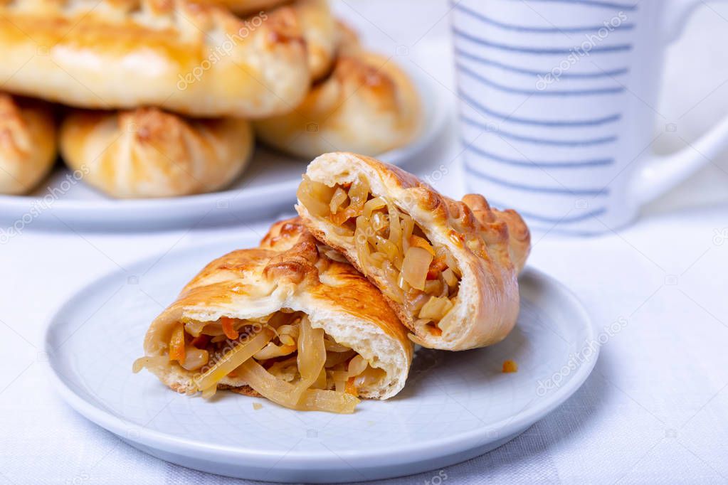Pies (pirozhki) with cabbage. Homemade baking. Traditional Russian and Ukrainian cuisine. In the background is a dish with pies. Close-up.