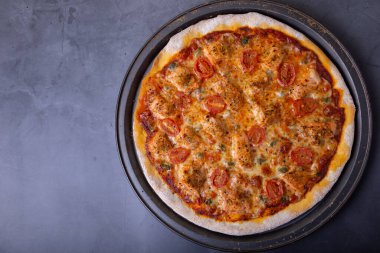 Somonlu pizza, domates ve kapari. Pizzanın tamamı siyah arka planda. Yakın çekim, üst görünüm, metin için yer.