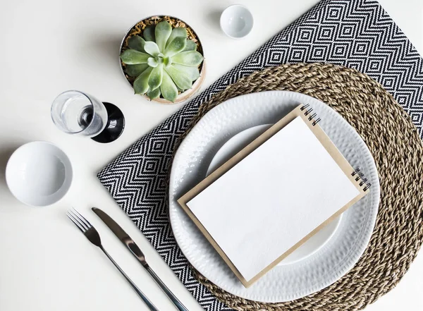 Накрываем стол. Посуда белая, одноцветные салфетки, столовые приборы, стекло и растения . — стоковое фото