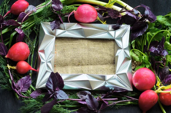 Çeşitli taze yeşillik, turp ve karanlık bir masa örtüsü üzerinde yer alan gümüş çerçeve, demet.