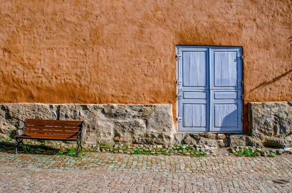 Bir antik dokulu duvar taş Bodrum, mavi bir kapı ve bir Bank ile.