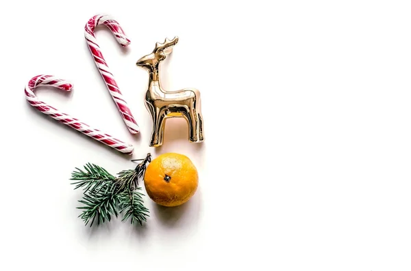 Año Nuevo composición inusual con ramas de abeto, dulces, mandarina y ciervos. Antecedentes navideños para presentación de obra o texto. Bonita tarjeta de felicitación. Vista desde arriba . — Foto de Stock