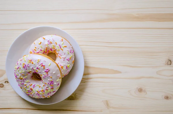 Çörek bir tabak ve ahşap bir masa. Fotoğraf tatlılar.