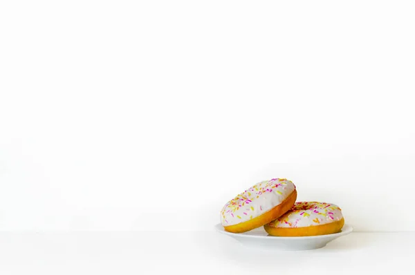 Beyaz zemin üzerinde bir tabakta donut. Minimalizm. Yan görünüm. Stok Fotoğraf