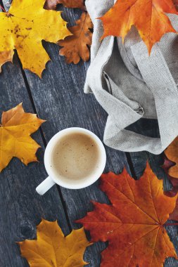 Kahve süt ve sırt çantası bir ahşap arka plan ve akçaağaç yaprakları