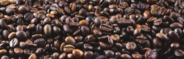 Background and texture of roasted coffee beans. Panorama. Side view.