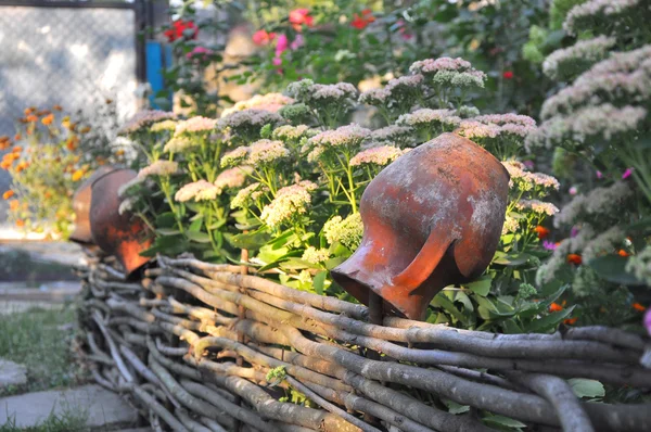 Wiejskie krajobrazy - starych glinianych garnków na koralowy ogrodzenia w pobliżu kwiaty — Zdjęcie stockowe