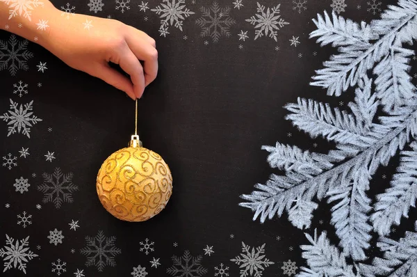 Mão feminina detém uma bola de Natal contra o fundo de um quadro — Fotografia de Stock