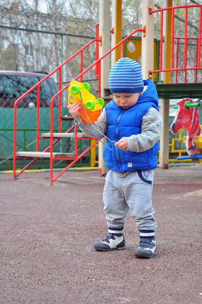 O menino brinca com um brinquedo no playground — Fotografia de Stock