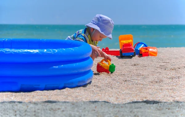 O menino joga brinquedos na areia na praia — Fotografia de Stock