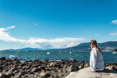 Vancouver, Kanada Kitsilano Plajı'nda bir kayaya oturan kız