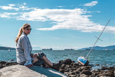 Vancouver, Kanada Kitsilano Plajı'nda bir kayaya oturan kız