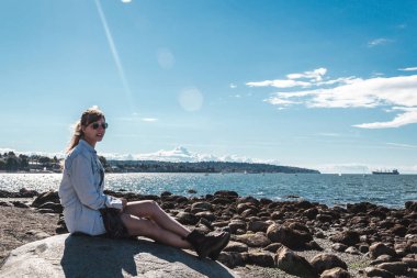 Vancouver, Kanada Kitsilano Plajı'nda bir kayaya oturan kız