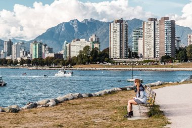 Downtown Vancouver, Kanada önünde bir bankta oturan kız