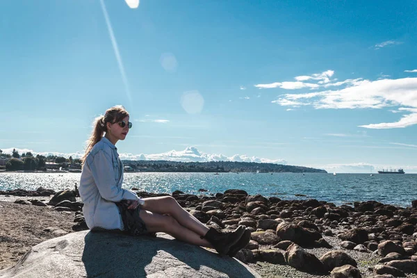 Meisje zittend op een rots op strand van Kitsilano in Vancouver, Canada — Stockfoto