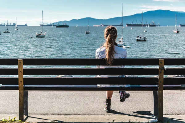 Meisje zittend op een bankje op het strand van Kitsilano in Vancouver, Canada — Stockfoto