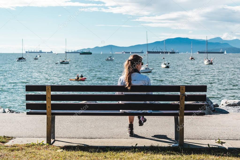 Girl Sitting on a Bench at Kitsilano Beach in Vancouver, Canada