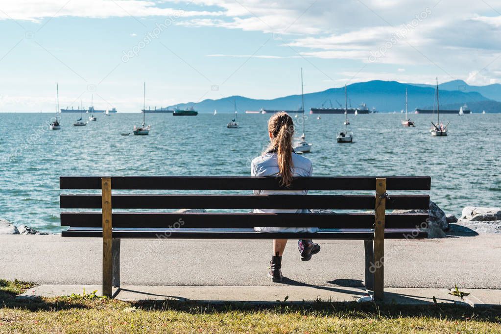 Girl Sitting on a Bench at Kitsilano Beach in Vancouver, Canada