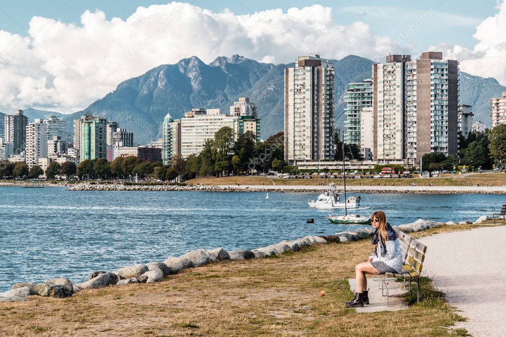 Girl Sitting on a Bench in front of Downtown Vancouver, Canada