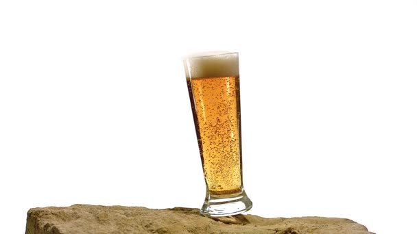 Vaso de cerveza cayendo y salpicando sobre piedra contra fondo blanco, cámara lenta — Vídeos de Stock