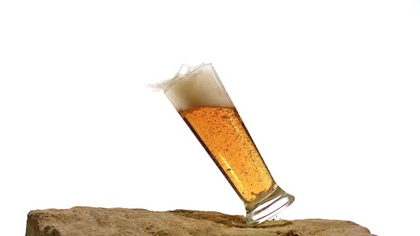 Glazen van bier vallen en spatten op steen tegen witte achtergrond, Slow motion — Stockvideo