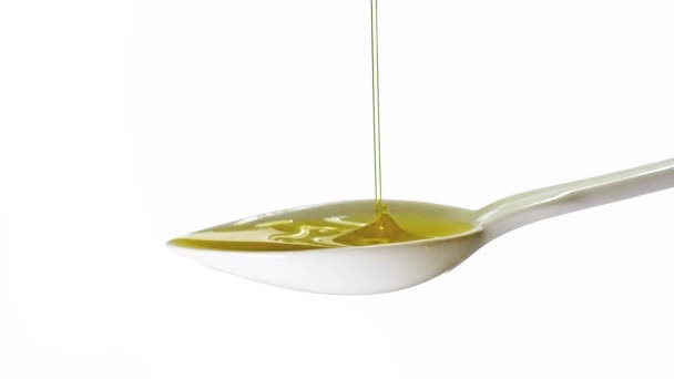 Оливки, падающие в ложку с оливковым маслом на белом фоне, медленное движение — стоковое видео