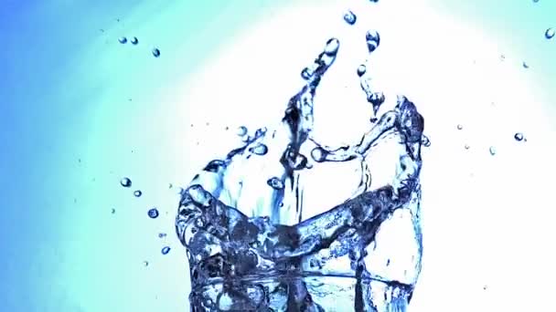 Разбрызгивание воды из стекла на голубом фоне, медленное движение — стоковое видео