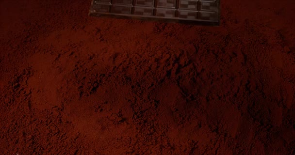 Шоколадная таблетка падает на шоколадный порошок — стоковое видео