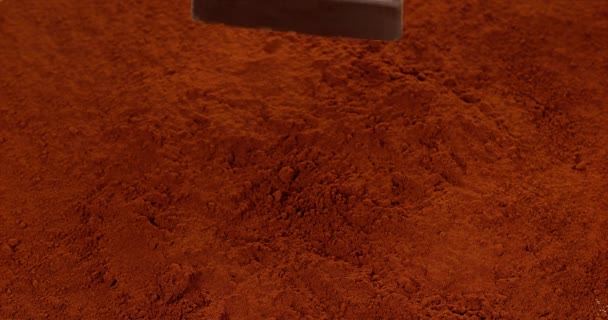 Tableta de chocolate cayendo en polvo de chocolate — Vídeos de Stock