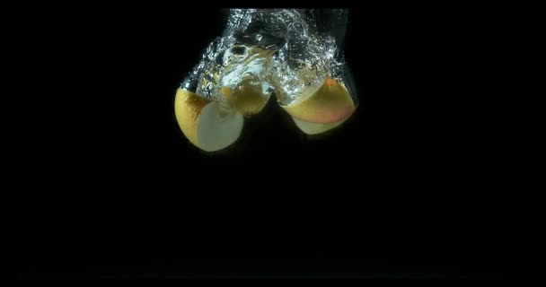 Pommes, malus domestica, Fruits entrant dans l'eau sur fond noir, Mouvement lent 4K — Video