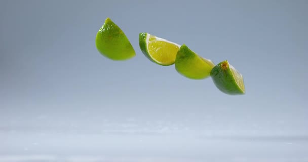 Limas verdes cayendo sobre el agua — Vídeos de Stock