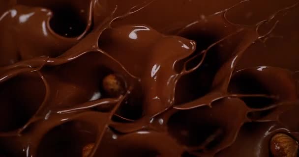 Avellanas cayendo en chocolate con leche — Vídeo de stock