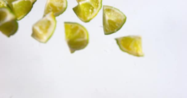 Limones verdes cayendo sobre el agua — Vídeos de Stock