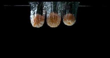 Clementines, narenciye reticulata, siyah arka plan, yavaş hareket 4 k suya düşen meyve