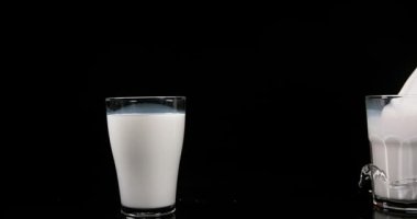 Süt cam splatching beyaz bir arka plana dayanır, yavaş hareket 4k