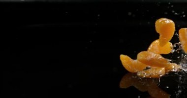 Clementines, narenciye reticulata, su siyah arka plan, yavaş hareket 4 k karşı düşen meyve