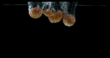 Clementines, narenciye reticulata, siyah arka plan, yavaş hareket 4 k suya düşen meyve