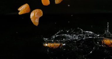 Clementines, narenciye reticulata, su siyah arka plan, yavaş hareket 4 k karşı düşen meyve