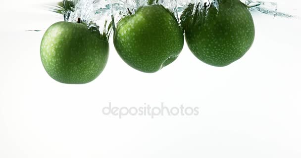 Manzanas Granny Smith, malus domestica, Frutas que entran al agua contra fondo blanco, cámara lenta 4K — Vídeo de stock