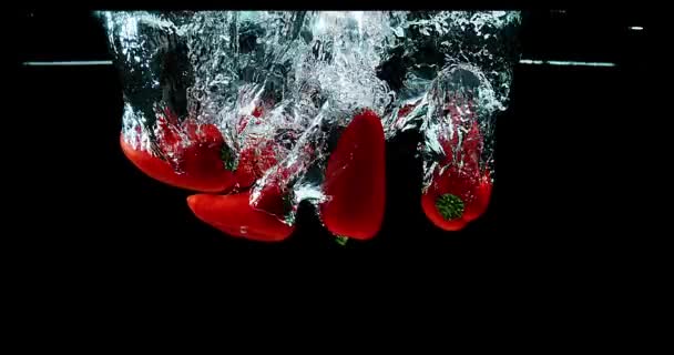 Красный сладкий перец, капсик однолетний, вегетарианский, падающий в воду на фоне черного, медленное движение 4K — стоковое видео