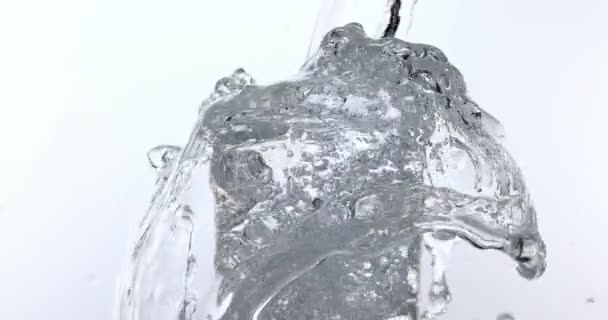 Agua que se vierte en vidrio contra fondo blanco, cámara lenta 4K — Vídeo de stock