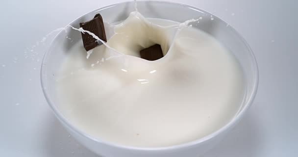 Chocolates caindo em um leite — Vídeo de Stock