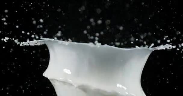 Boule de golf et lait explosif sur fond noir, ralenti 4K 